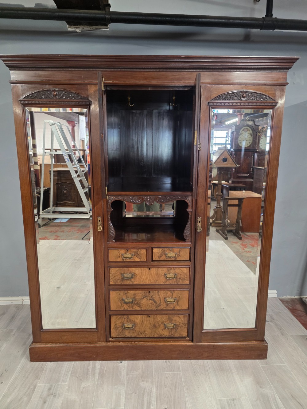 A late Victorian walnut combination wardrobe featuring twin mirrored doors flanking a central section of carved cupboards, an open shelf niche, and five burr walnut drawers. View III