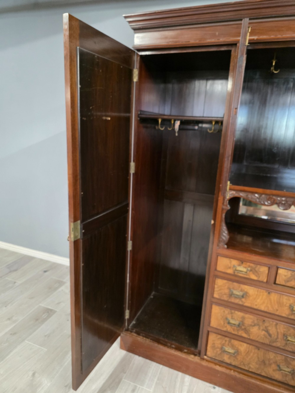 A late Victorian walnut combination wardrobe featuring twin mirrored doors flanking a central section of carved cupboards, an open shelf niche, and five burr walnut drawers. View IV