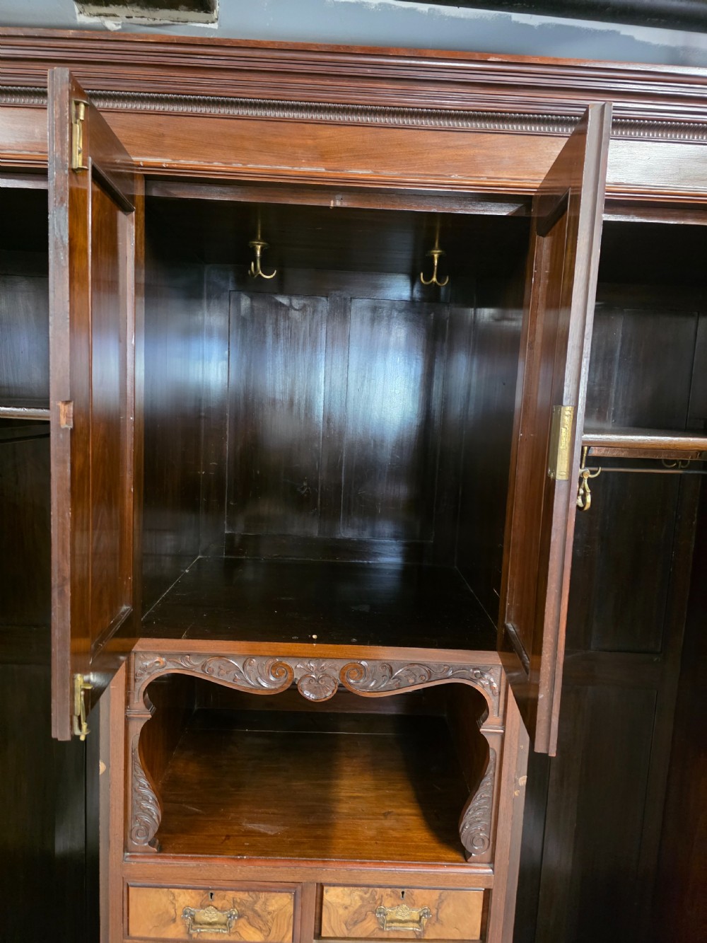 A late Victorian walnut combination wardrobe featuring twin mirrored doors flanking a central section of carved cupboards, an open shelf niche, and five burr walnut drawers. View V