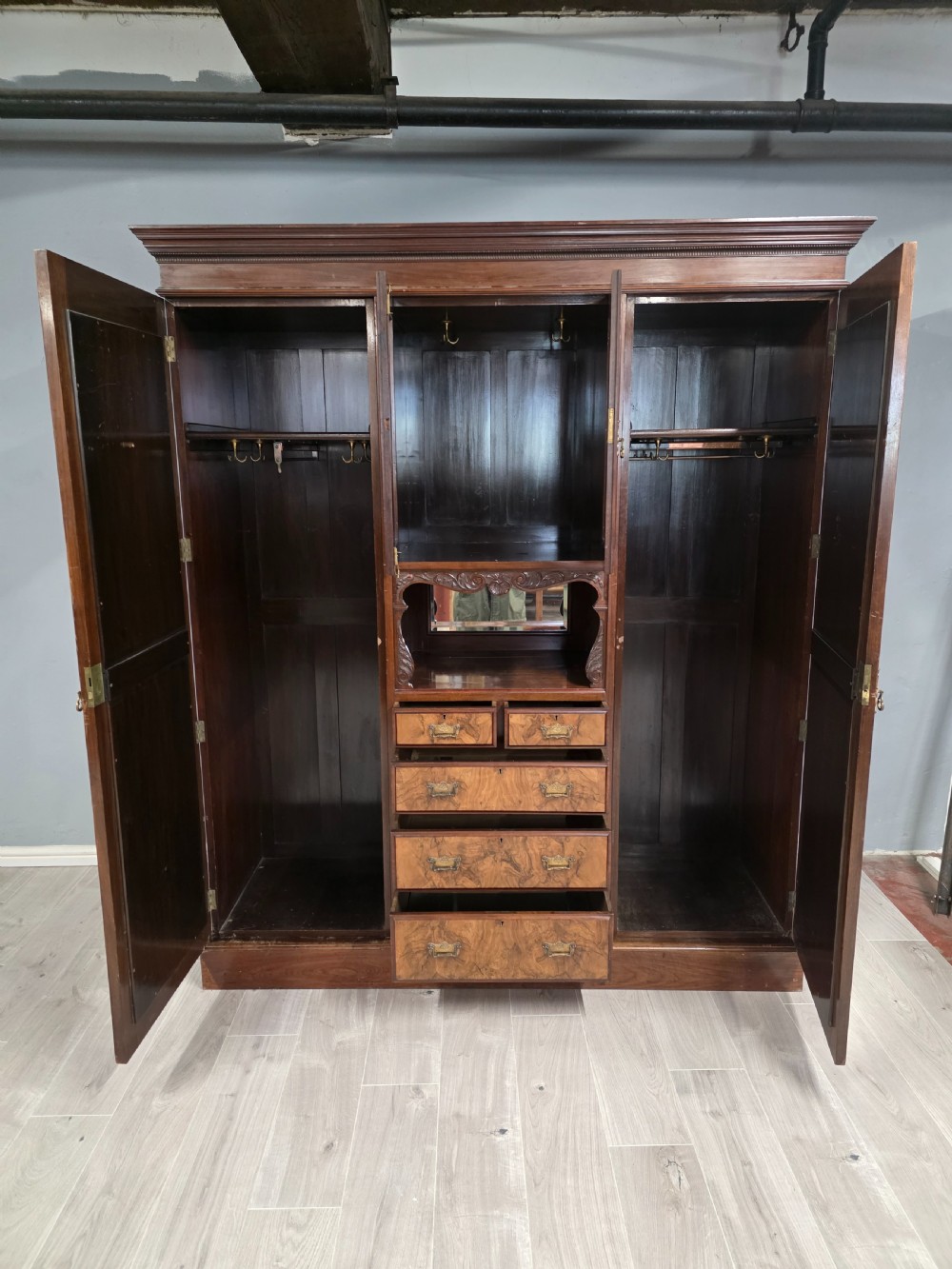 A late Victorian walnut combination wardrobe featuring twin mirrored doors flanking a central section of carved cupboards, an open shelf niche, and five burr walnut drawers. View VIII