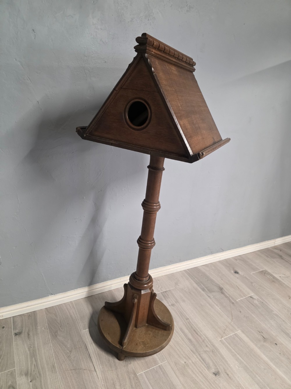 An antique Victorian oak church lectern featuring a sloped book rest with dentil moulding, a turned central column, and a circular base with bracket supports. View III