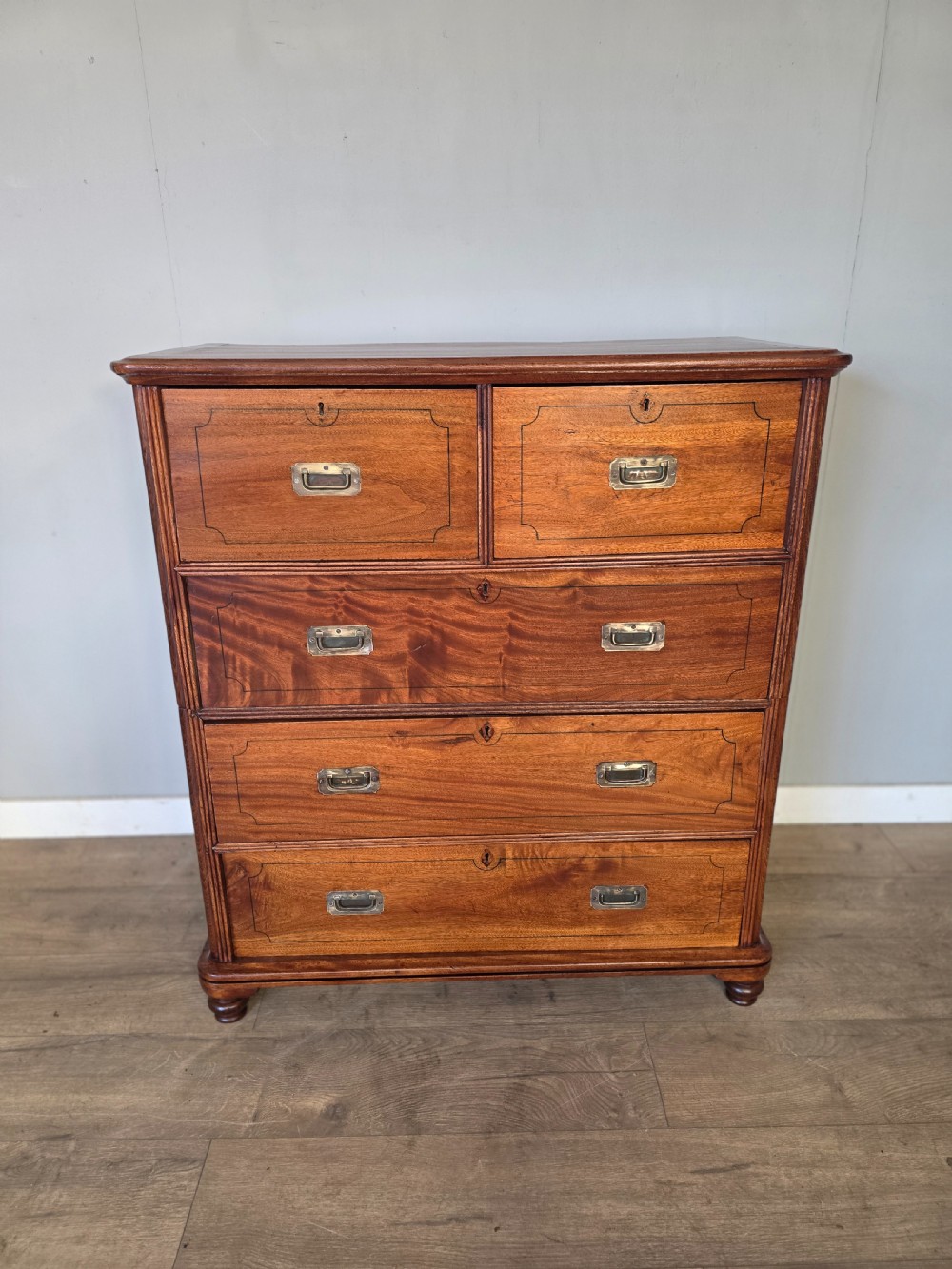 A 19th-century teak military campaign chest of drawers featuring a two-part split design with flush brass handles and turned feet. View III