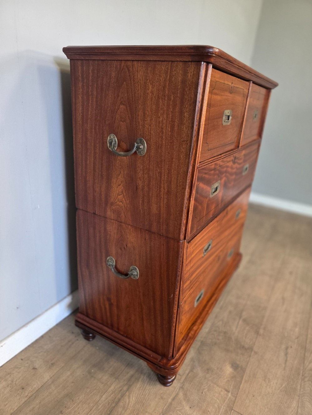 A 19th-century teak military campaign chest of drawers featuring a two-part split design with flush brass handles and turned feet. View VIII