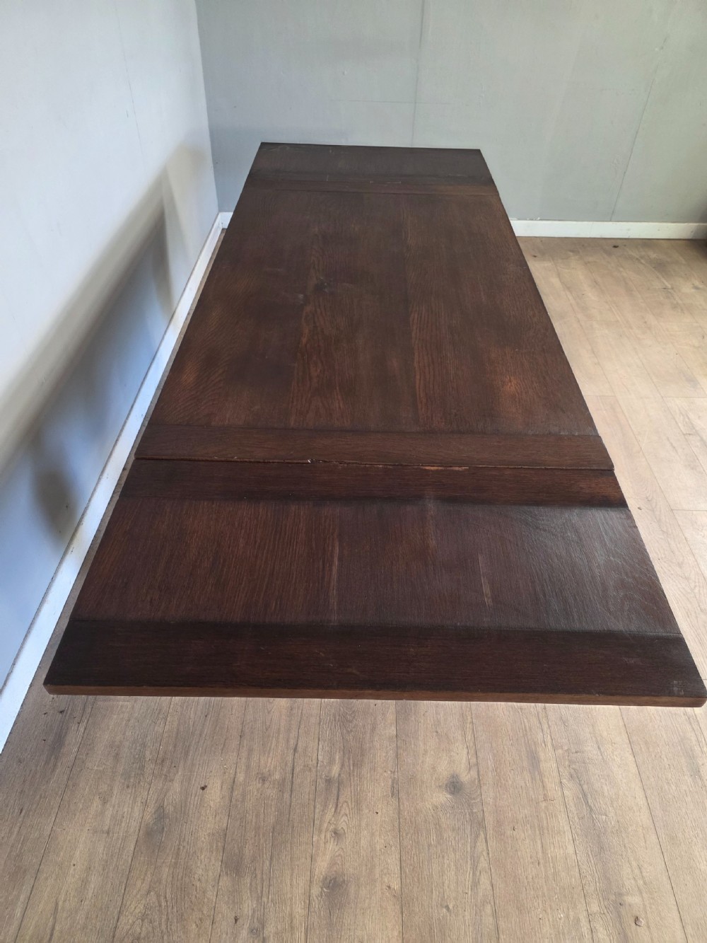 A solid dark oak extending dining table featuring carved bulbous legs, a decorative foliage apron, and a stretcher base. View XII