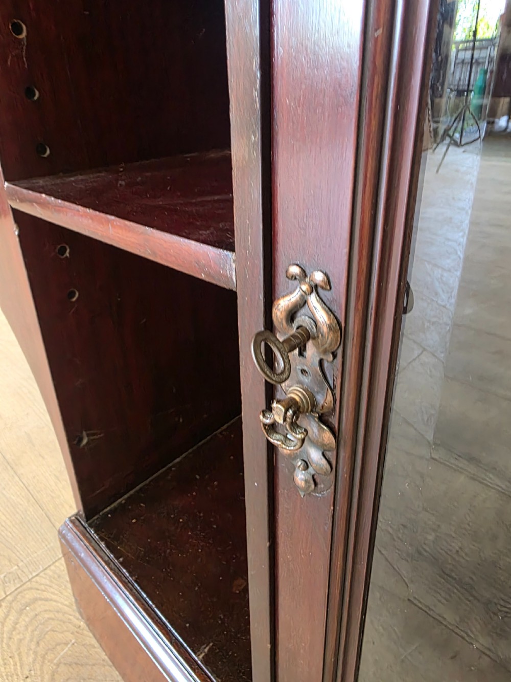 An antique dark mahogany Arts and Crafts display bookcase featuring a top galleried balustrade, open side shelves with pierced cut-outs, two glazed cabinet doors, and two middle drawers. View V