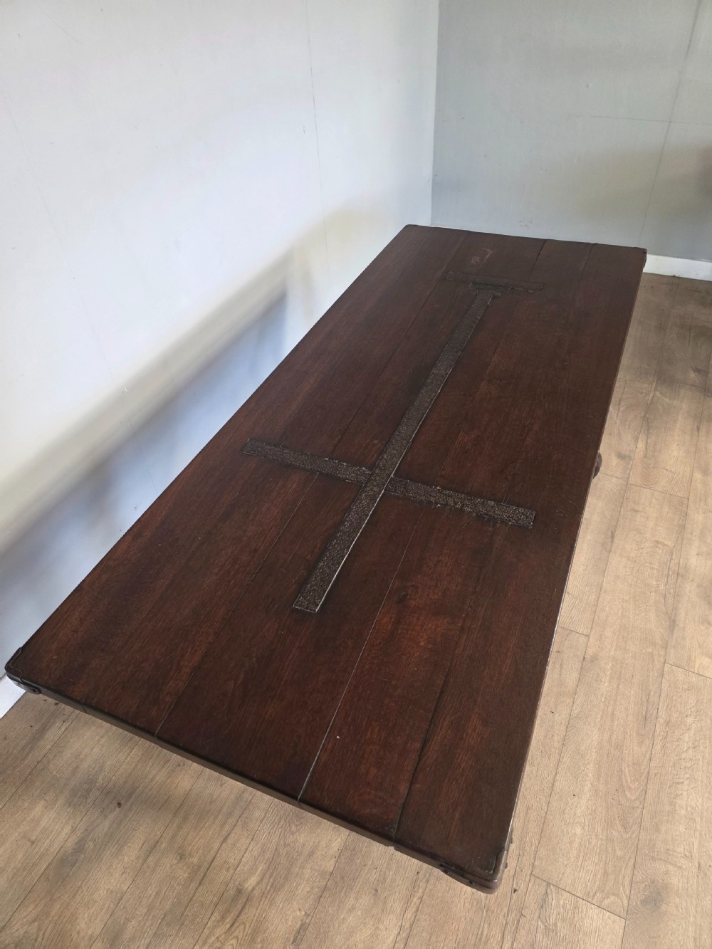A dark brown oak refectory table featuring shaped trestle legs and a hand-forged wrought iron scrollwork stretcher beneath a rectangular top. View III