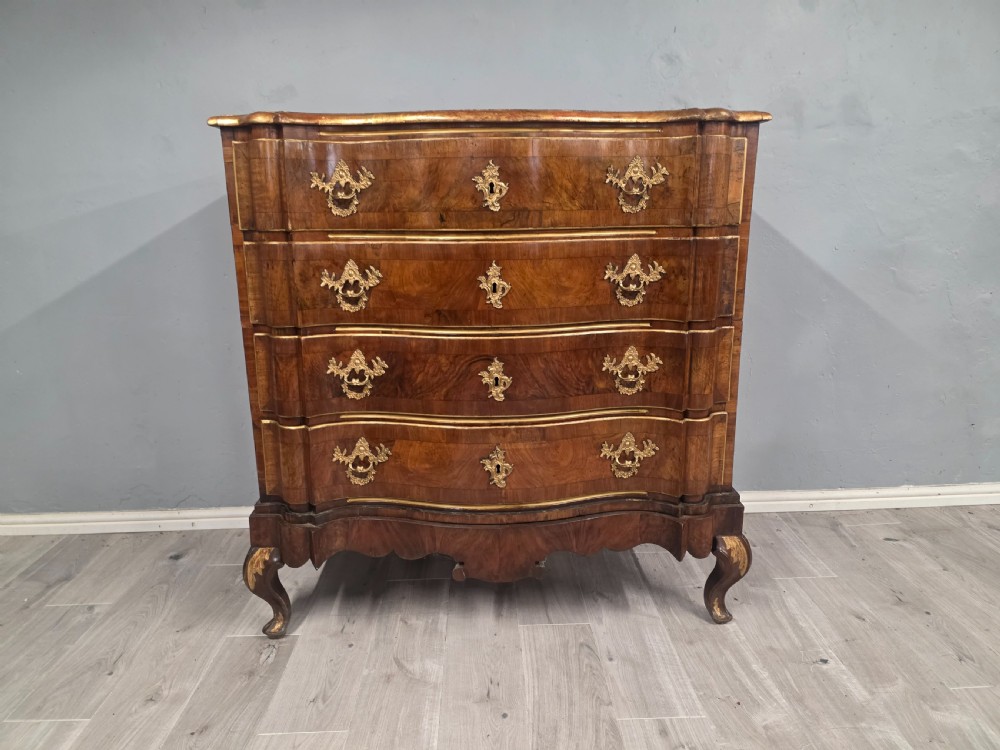 An 18th-century walnut chest of drawers featuring a serpentine front, four drawers, ornate brass handles, and short cabriole legs. View II