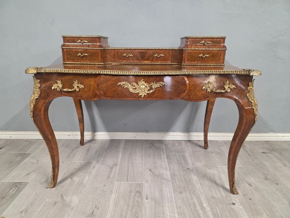 A 19th-century French Rococo Revival writing desk crafted from burr walnut with gilt-bronze mounts, a central leather writing insert, and a raised superstructure of drawers. View II