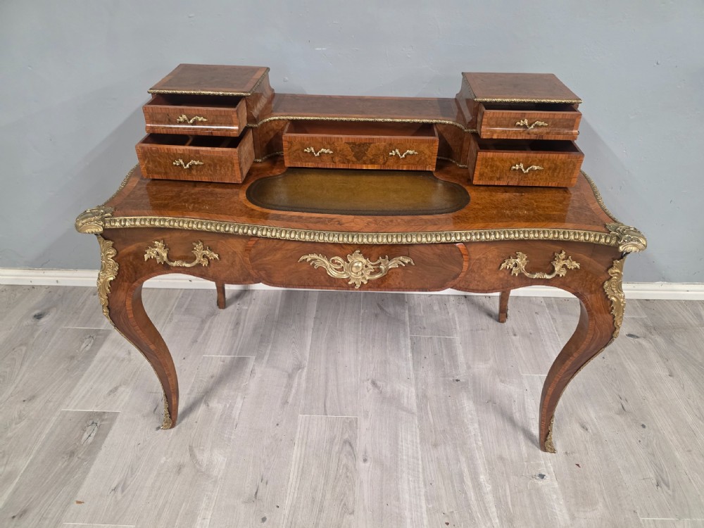 A 19th-century French Rococo Revival writing desk crafted from burr walnut with gilt-bronze mounts, a central leather writing insert, and a raised superstructure of drawers. View V