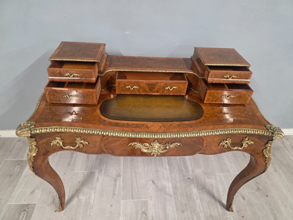 A 19th-century French Rococo Revival writing desk crafted from burr walnut with gilt-bronze mounts, a central leather writing insert, and a raised superstructure of drawers. View VII