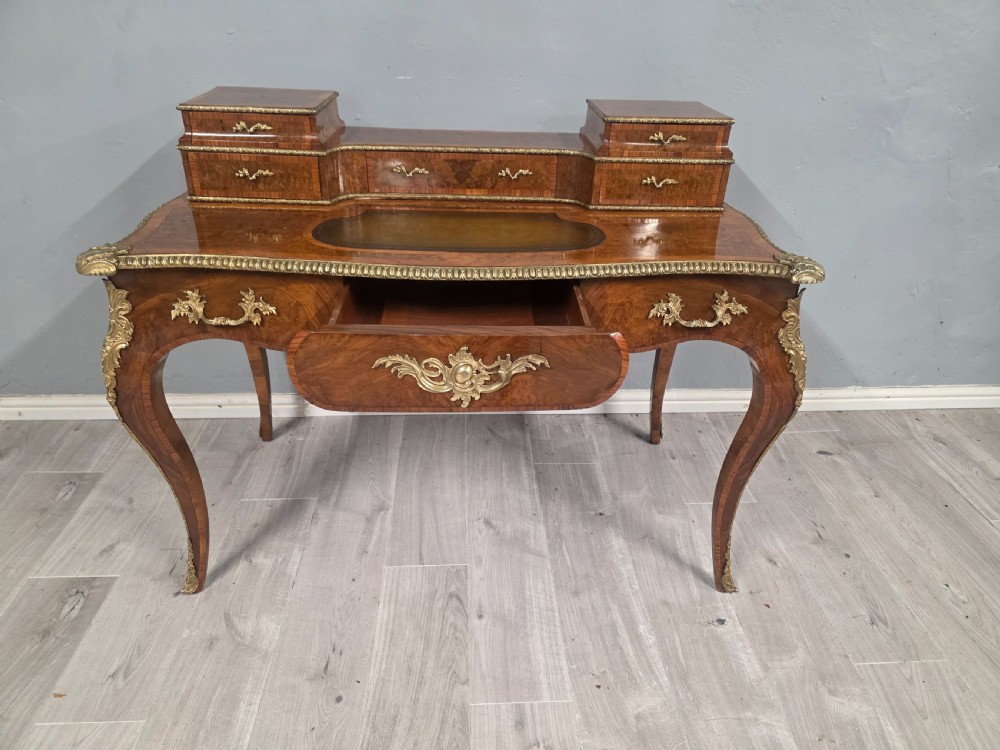 A 19th-century French Rococo Revival writing desk crafted from burr walnut with gilt-bronze mounts, a central leather writing insert, and a raised superstructure of drawers. View XI