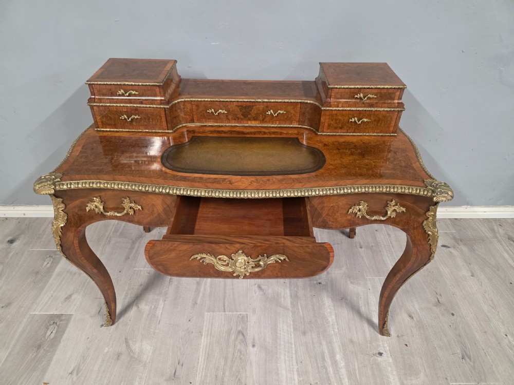 A 19th-century French Rococo Revival writing desk crafted from burr walnut with gilt-bronze mounts, a central leather writing insert, and a raised superstructure of drawers. View XII