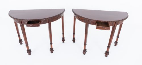 fig 1. A pair of demilune mahogany console tables with carved drapery aprons and slender tapered legs ending in decorative feet.