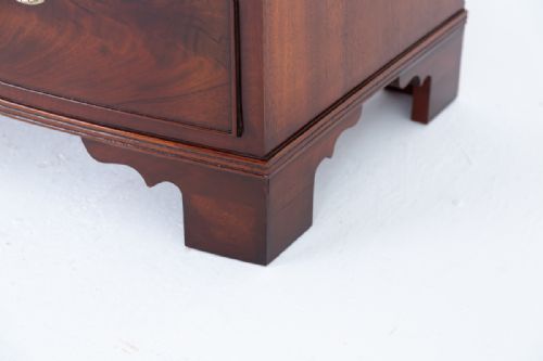 fig 1. A Regency mahogany bow-front chest of drawers featuring three graduated drawers with oval brass handles and bracket feet.