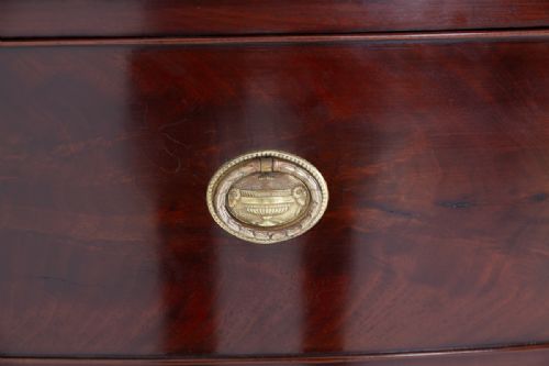 fig 2. A Regency mahogany bow-front chest of drawers featuring three graduated drawers with oval brass handles and bracket feet.