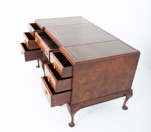 A Queen Anne style burr walnut kneehole desk featuring an inset dark leather writing top, brass drop handles, and cabriole legs. View VII