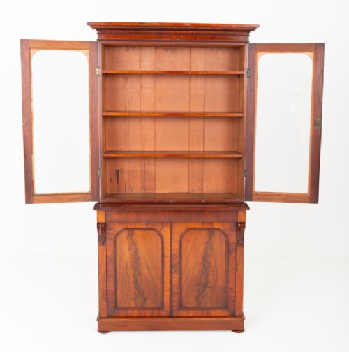 A two-piece Victorian mahogany library bookcase featuring arched glazed doors on the upper section and flame mahogany cupboard doors on the lower base. View VI