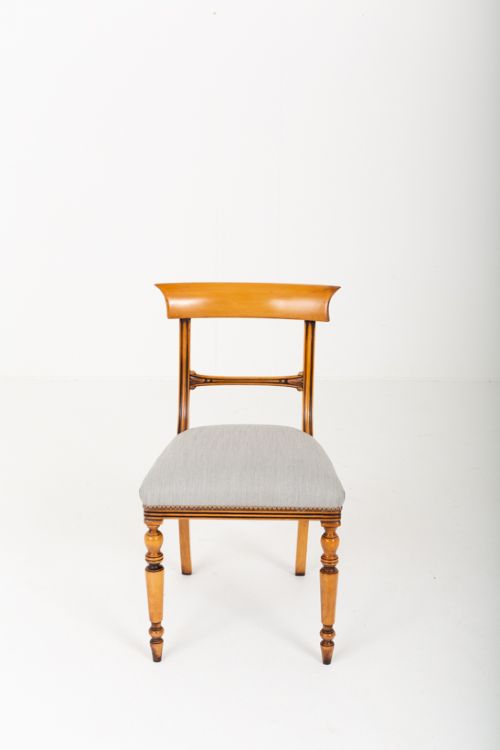 A set of twelve Regency style dining chairs crafted from honey-toned satin birch wood with curved crest rails, turned front legs, and light blue upholstered seats. View II