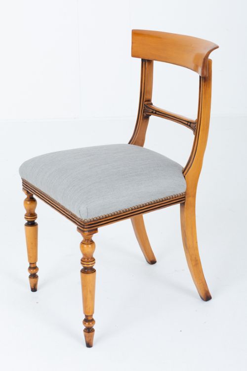 A set of twelve Regency style dining chairs crafted from honey-toned satin birch wood with curved crest rails, turned front legs, and light blue upholstered seats. View IV