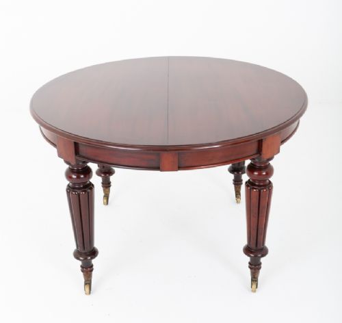 An antique dark mahogany extending dining table with a polished top, central removable leaves, and fluted turned legs on brass castors. View VIII