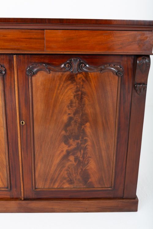 A nineteenth-century Victorian mahogany side cabinet featuring two flame mahogany veneered doors flanked by decorative carved corbels. View III