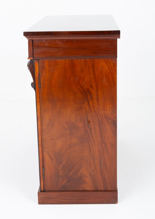 A nineteenth-century Victorian mahogany side cabinet featuring two flame mahogany veneered doors flanked by decorative carved corbels. View IV