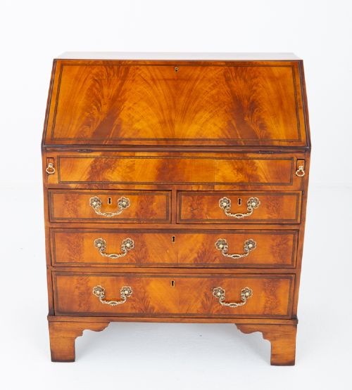An antique mahogany writing bureau featuring a sloped fall-front flap over four graduated drawers with ornate brass handles and bracket feet. View V