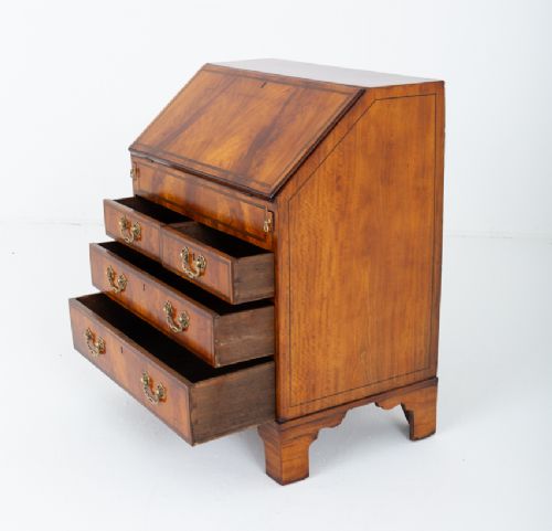 An antique mahogany writing bureau featuring a sloped fall-front flap over four graduated drawers with ornate brass handles and bracket feet. View VII