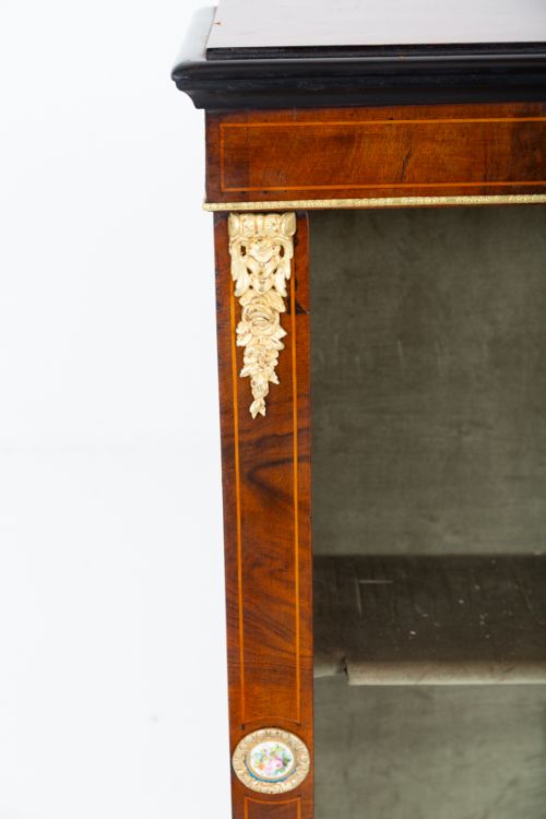 fig 1. A Victorian burr walnut open bookcase featuring two open shelves, ebonised top trim, gilt brass mounts, and ceramic plaque details.
