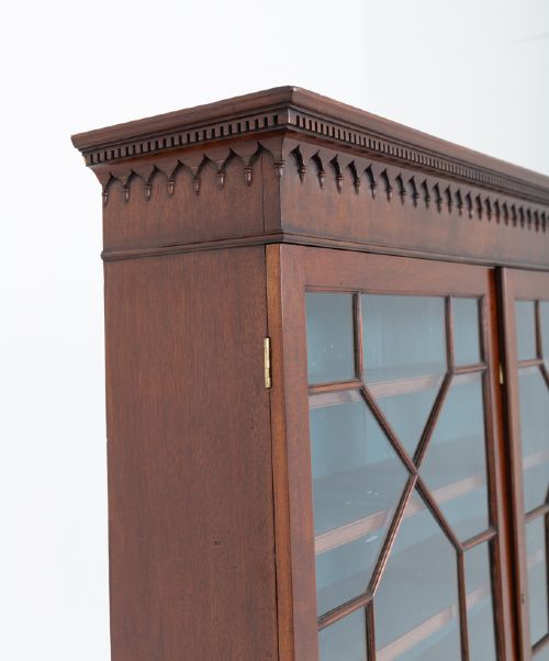 fig 1. A Georgian mahogany two-piece bookcase on chest featuring an astragal glazed upper cabinet, dentil cornice, and a chest of drawers resting on bracket feet.