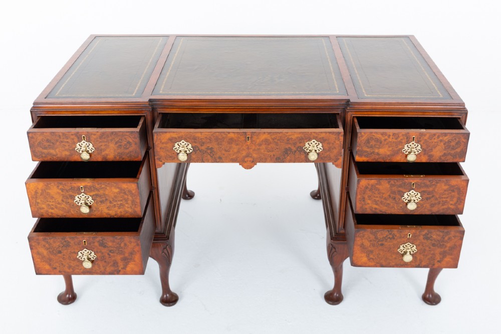 A Queen Anne style burr walnut kneehole desk featuring an inset dark leather writing top, brass drop handles, and cabriole legs. View II