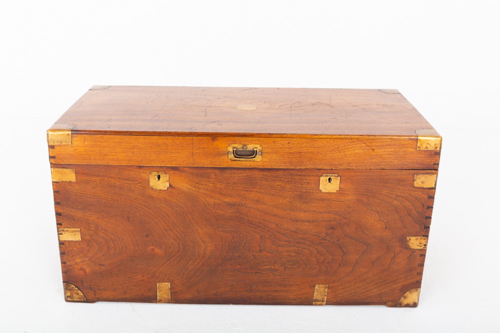 A rectangular camphor wood military campaign trunk featuring brass corner mounts, flush-fitting brass hardware, and iron side carrying handles. View V