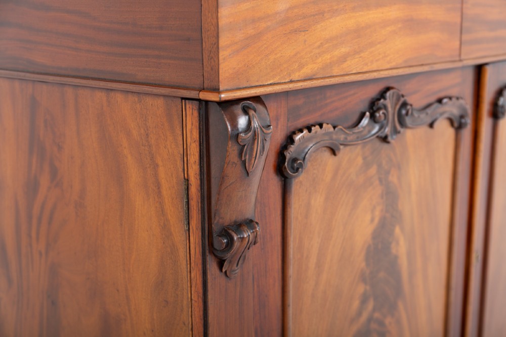 A nineteenth-century Victorian mahogany side cabinet featuring two flame mahogany veneered doors flanked by decorative carved corbels. View II