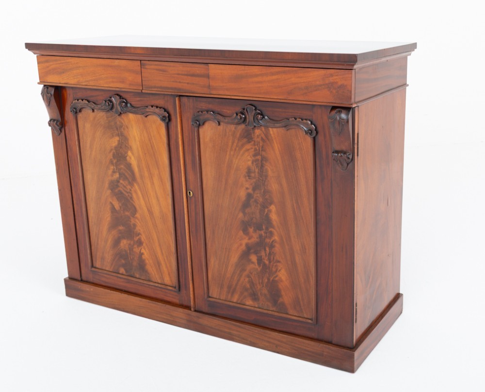 A nineteenth-century Victorian mahogany side cabinet featuring two flame mahogany veneered doors flanked by decorative carved corbels. View V