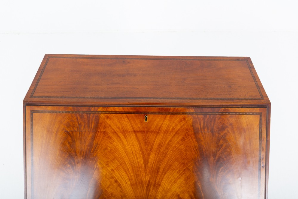 An antique mahogany writing bureau featuring a sloped fall-front flap over four graduated drawers with ornate brass handles and bracket feet. View III