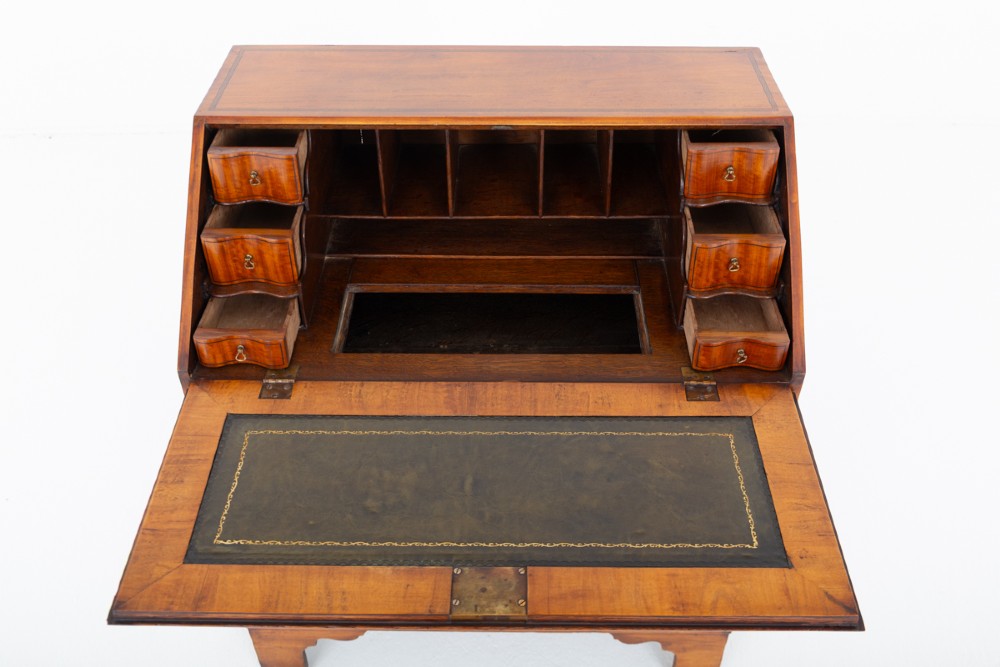 An antique mahogany writing bureau featuring a sloped fall-front flap over four graduated drawers with ornate brass handles and bracket feet. View VIII