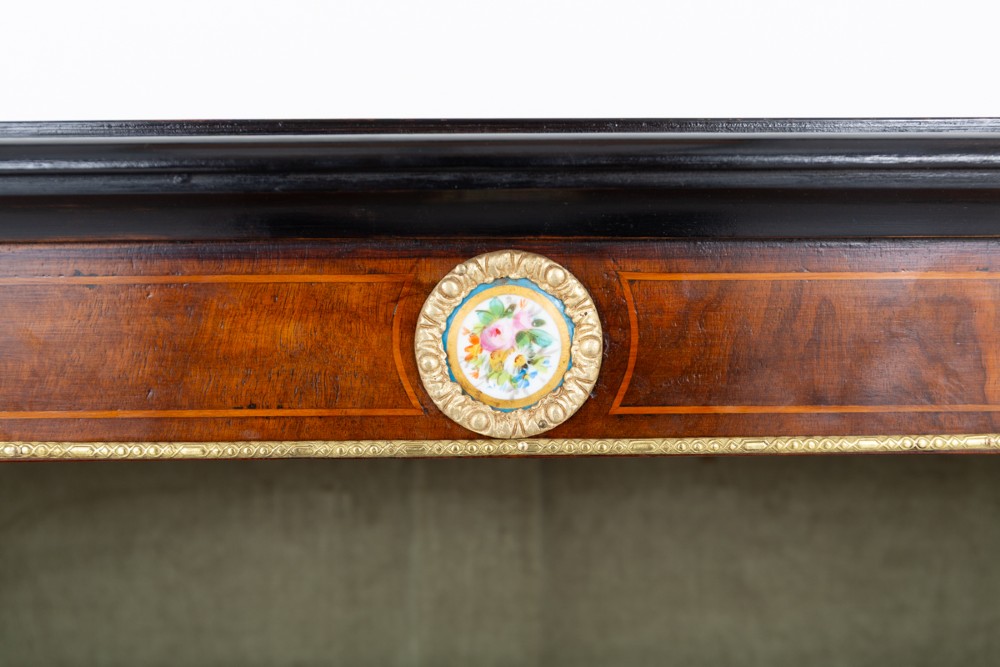 A Victorian burr walnut open bookcase featuring two open shelves, ebonised top trim, gilt brass mounts, and ceramic plaque details. View III