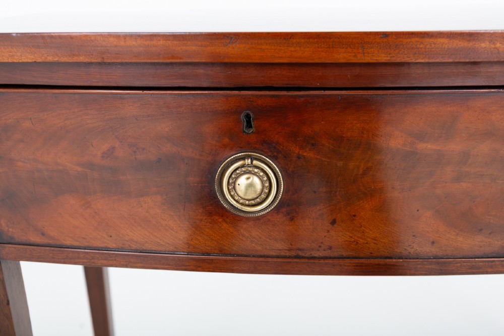 A Regency mahogany bow-front side table featuring two drawers with brass ring handles and slender square tapered legs. View IV