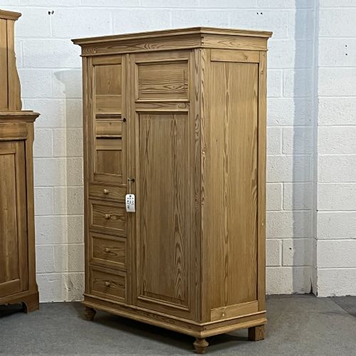 fig 1. A freestanding 1930s pine compactum wardrobe featuring a upper mirror above four drawers on the left and a tall panelled door on the right.