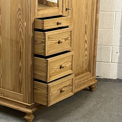 fig 4. A freestanding 1930s pine compactum wardrobe featuring a upper mirror above four drawers on the left and a tall panelled door on the right.