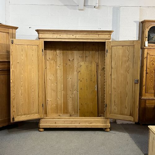 fig 1. A large French pine double wardrobe featuring twin panelled doors, iron escutcheons, a moulded cornice, and rounded feet.