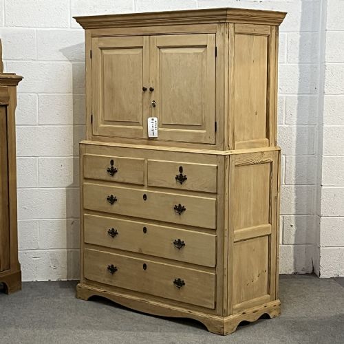 fig 1. A nineteenth-century pale pine linen press featuring a double-door top cupboard set above two short and three long graduated drawers with brass handles.
