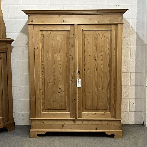 fig 1. A freestanding 1930s double pine wardrobe featuring twin recessed panel doors, a moulded top cornice, and a natural timber grain.