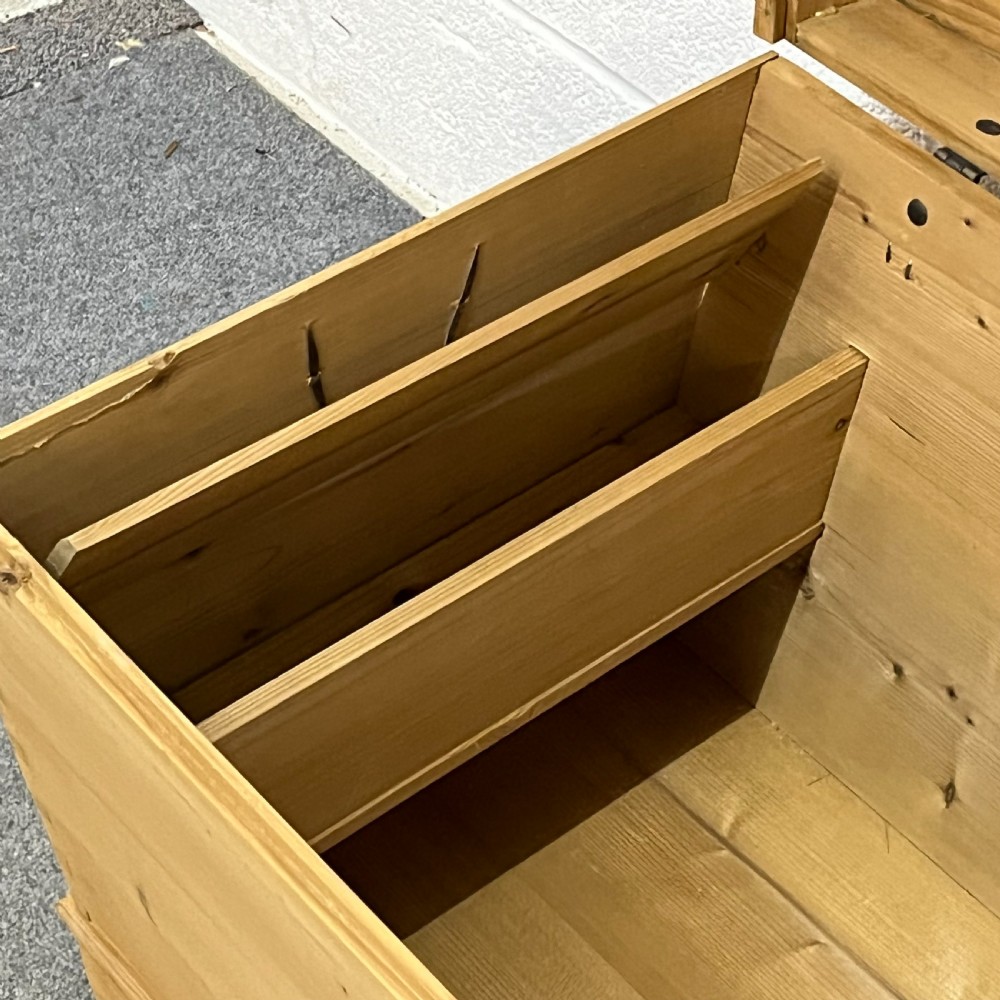 A solid honey-toned pine dome top trunk with visible corner dovetail joints, metal side carrying handles, and a central keyhole escutcheon. View VI