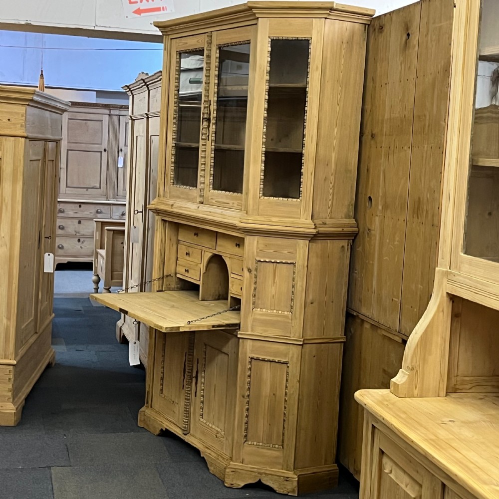 A large natural pine secretaire bookcase featuring glazed upper doors, a fold-down desk surface with internal drawers, and a lower two-door cupboard. View V