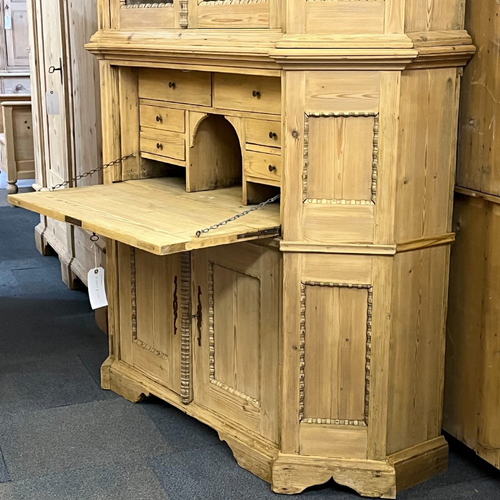 A large natural pine secretaire bookcase featuring glazed upper doors, a fold-down desk surface with internal drawers, and a lower two-door cupboard. View VI