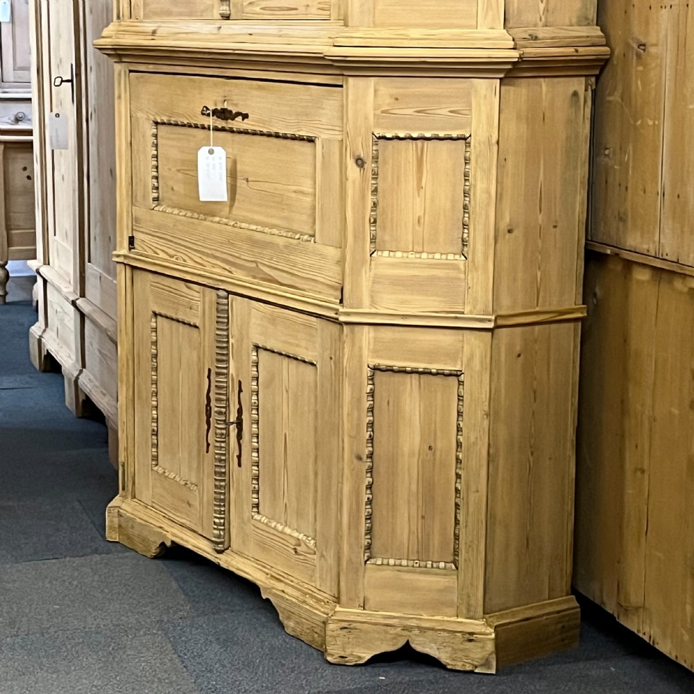 A large natural pine secretaire bookcase featuring glazed upper doors, a fold-down desk surface with internal drawers, and a lower two-door cupboard. View VII