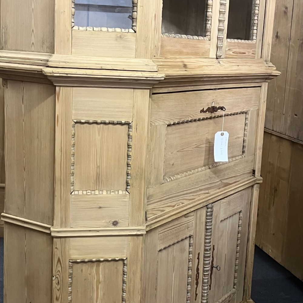 A large natural pine secretaire bookcase featuring glazed upper doors, a fold-down desk surface with internal drawers, and a lower two-door cupboard. View XIV