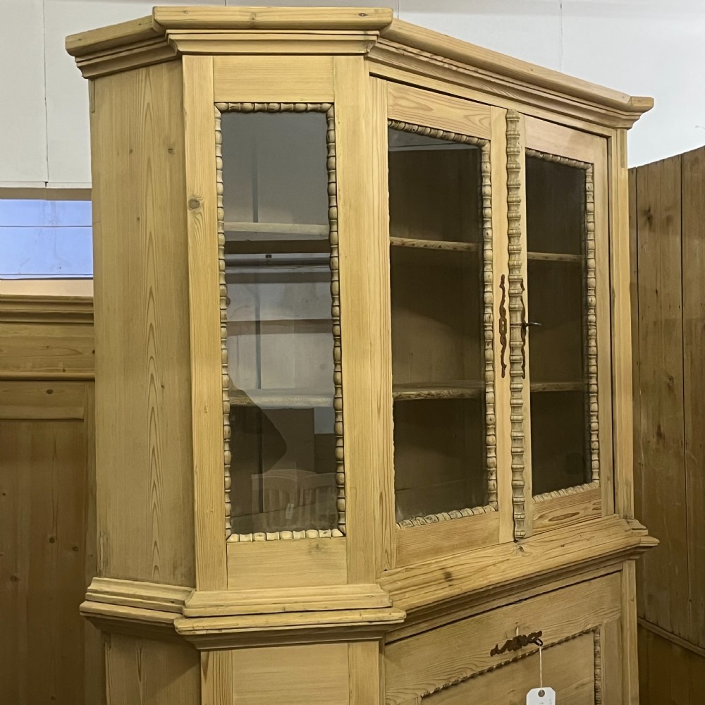 A large natural pine secretaire bookcase featuring glazed upper doors, a fold-down desk surface with internal drawers, and a lower two-door cupboard. View XV
