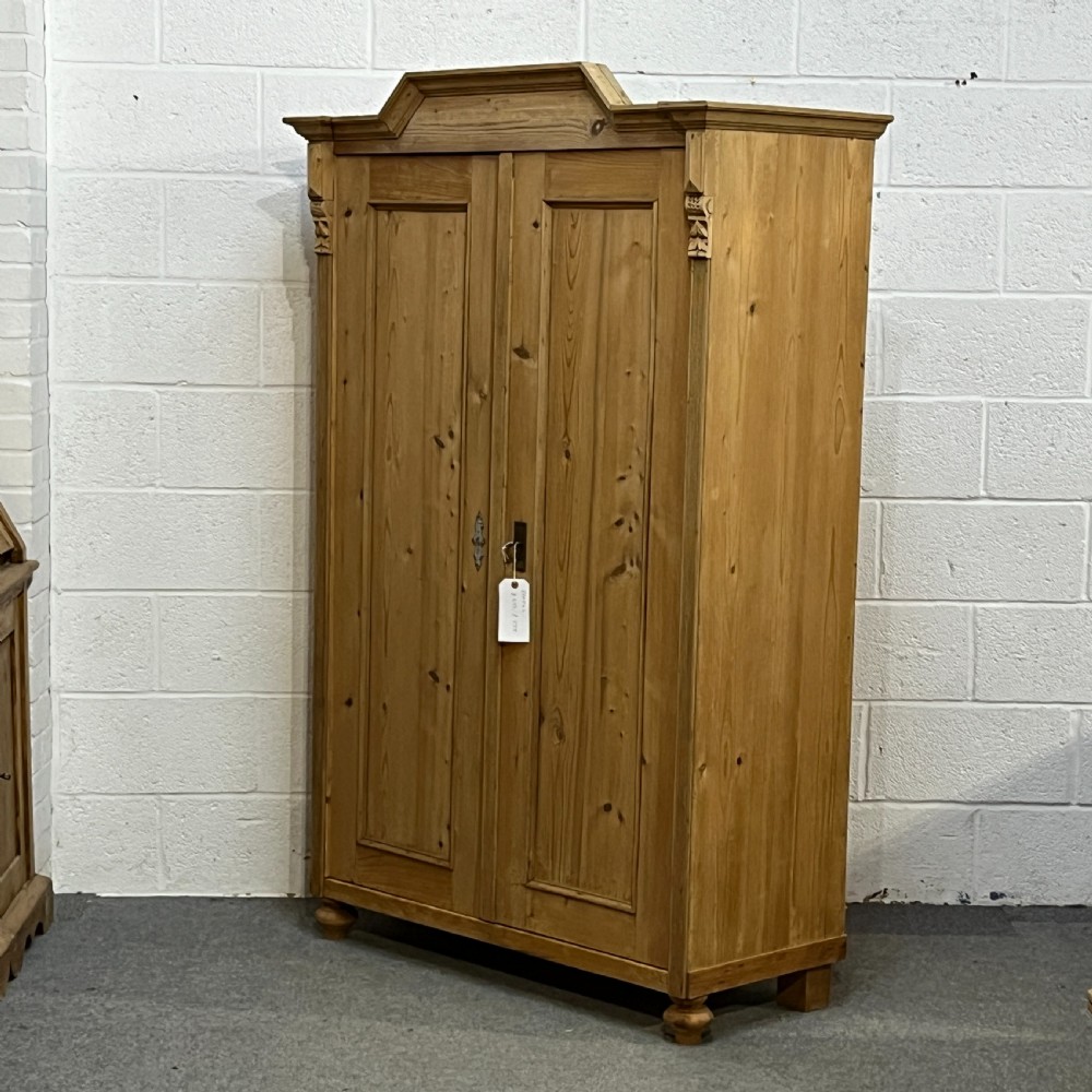 A tall Victorian pine two-door cupboard featuring field-panelled doors, turned bun feet, and a shaped bonnet top pediment. View II